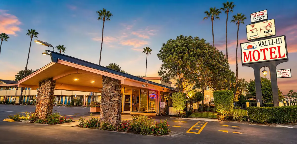 Valli Hi Motel entrance at dusk with illuminated sign and palm trees